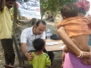 Dr Dipankar Thakuria, Medical Officer, Lakhimpur Boat Clinic checking up a child as the mother(back towards us)looks on at the inaugural camp .