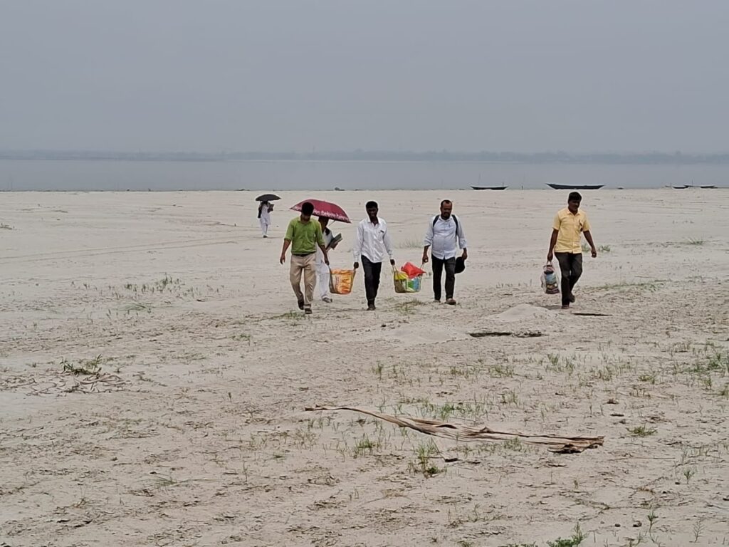 The Bongaigaon Boat Clinic team walking to the camp site carrying medicines and other necessary camp essential for a general check up and routine immunization session for targeted beneficiary from Satsobigha char in May 2023